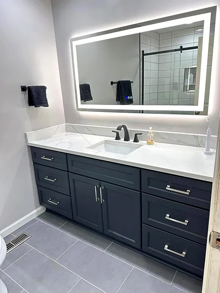 Navy bathroom vanity with lighted mirror and quartz top by WoodArt Cabinets San Antonio