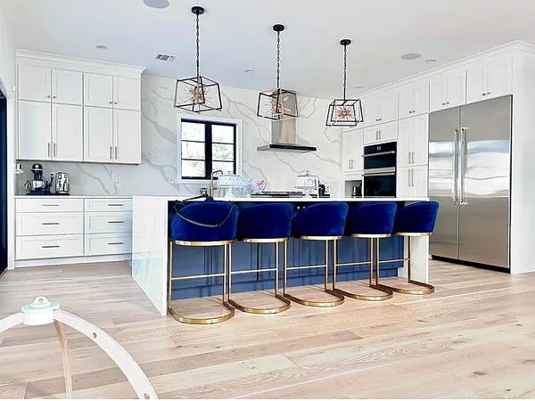 white kitchen with blue velvet bar stools and gold accents by WoodArt Cabinets San Antonio