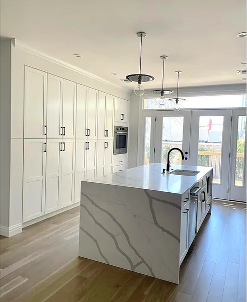 White kitchen with quartz waterfall island and black faucet by WoodArt Cabinets San Antonio