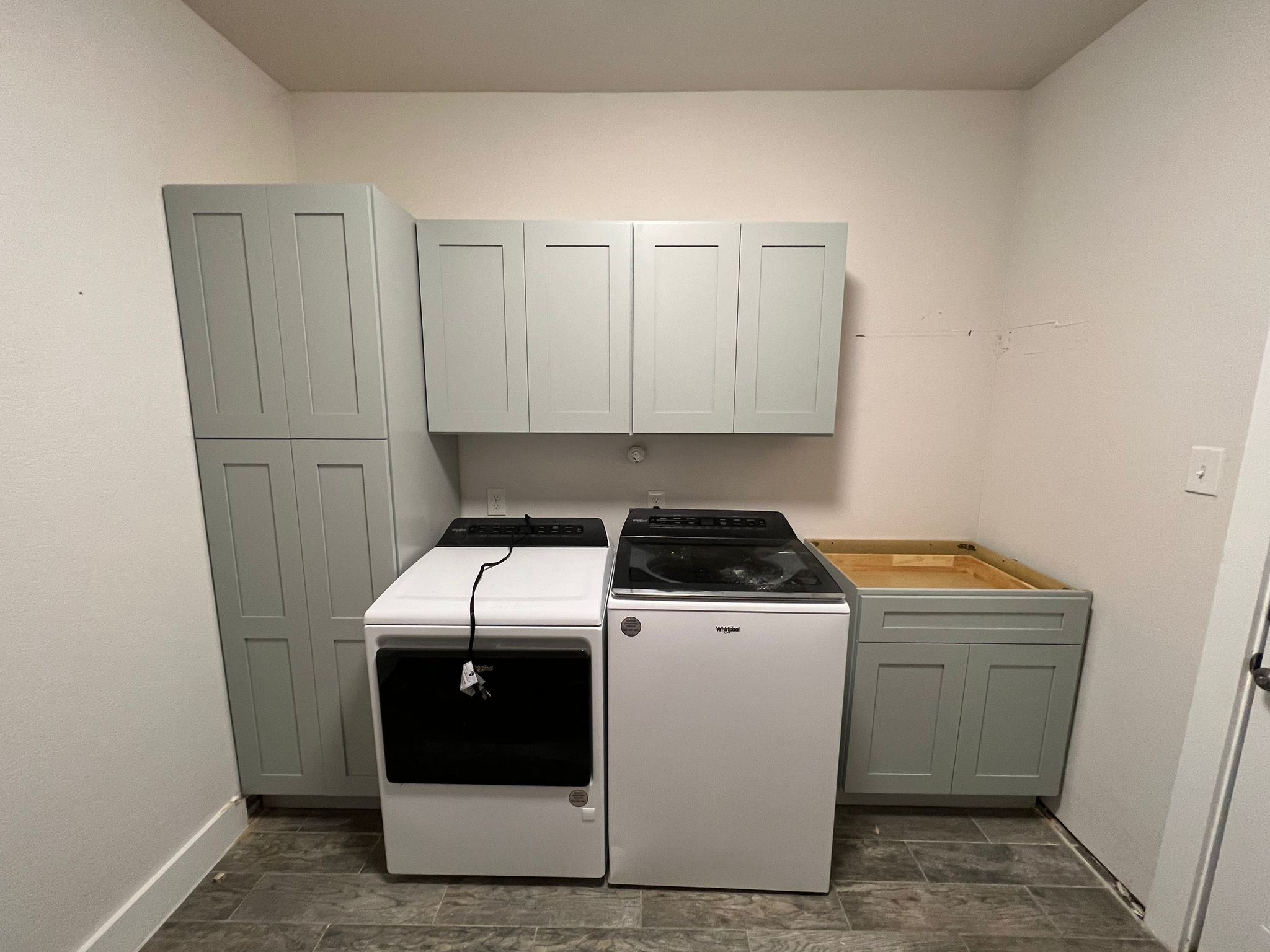 Custom white raised-panel laundry cabinets with quartz countertop, brass hardware, and undermount sink — WoodArt Cabinets San Antonio